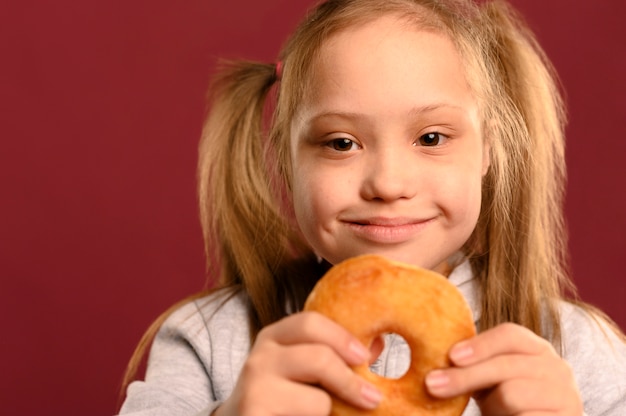 Entzückendes junges Mädchen, das köstlichen Donut hält