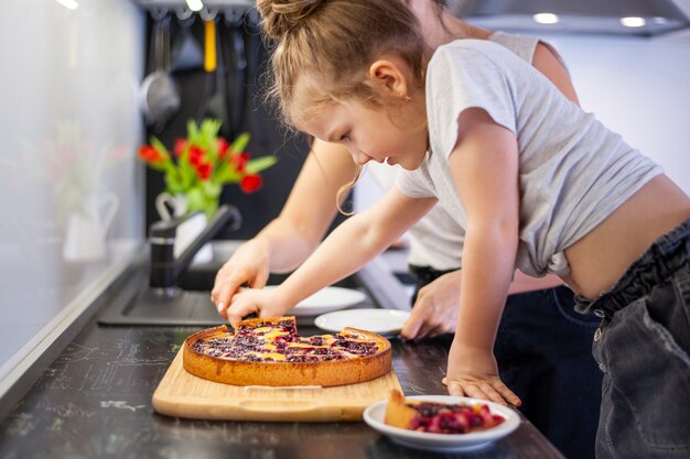 Entzückendes junges Mädchen, das Kuchen mit Mutter teilt