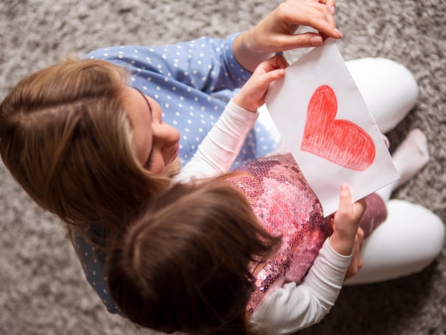 Entzückendes junges Mädchen, das Zeichnung zu ihrer Mutter zeigt