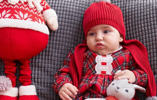 Entzückendes kaukasisches Baby, das zu Hause auf Sofa mit entspanntem Ausdruck sitzt