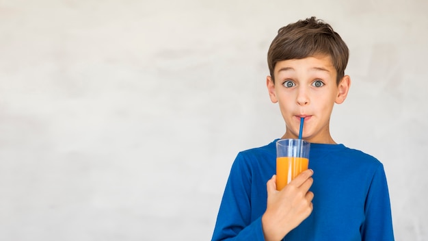 Entzückendes Kind, das etwas Orangensaft trinkt