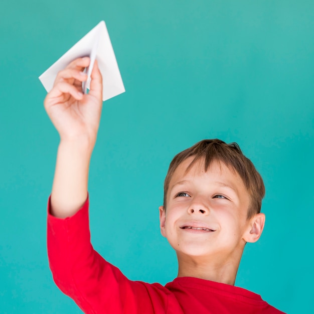 Entzückendes kind, das mit einem papierflugzeug spielt