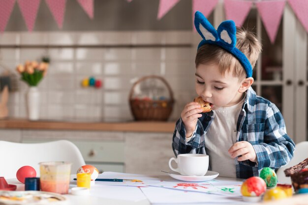 Entzückendes kleines Kind mit Hasenohren, die einen Keks essen