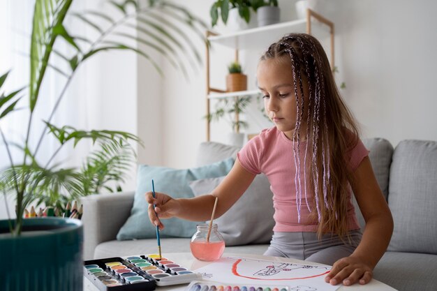 Entzückendes kleines Mädchen, das zu Hause auf Papier malt