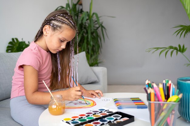 Kostenloses Foto entzückendes kleines mädchen, das zu hause auf papier malt