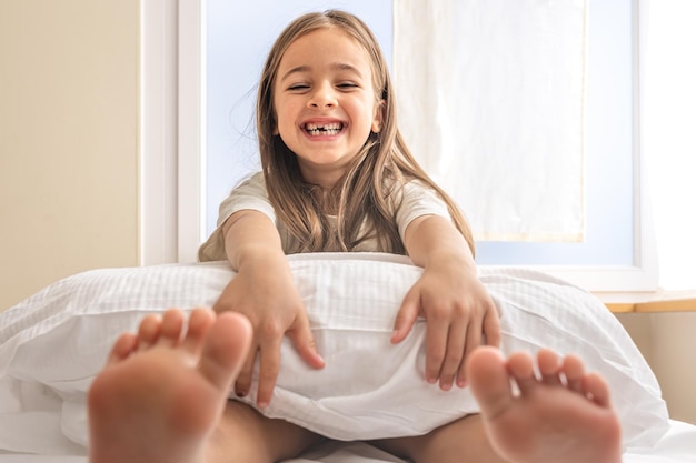 Entzückendes kleines Mädchen in ihrem Bett am frühen Morgen