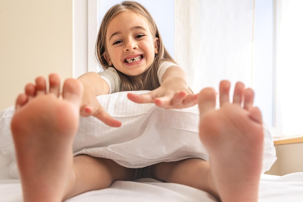 Entzückendes kleines Mädchen in ihrem Bett am frühen Morgen