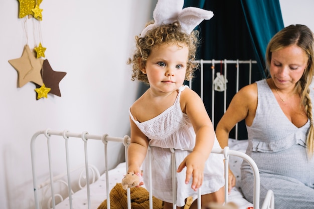 Entzückendes Mädchen auf Bett mit Mutter