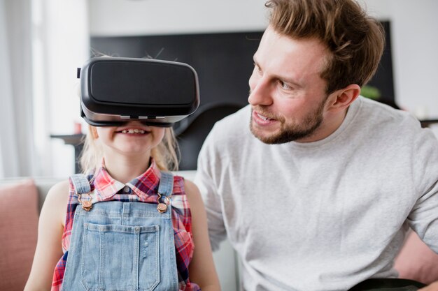 Entzückendes Mädchen in VR-Schutzbrillen nähern sich Vater