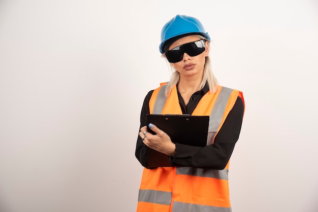 Erbauerin mit Schutzbrille, die Zwischenablage hält. Hochwertiges Foto