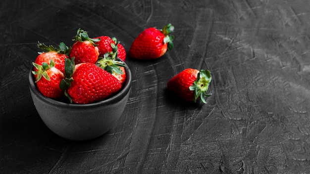 Kostenloses Foto erdbeeren in der schüssel auf schwarzer tabelle