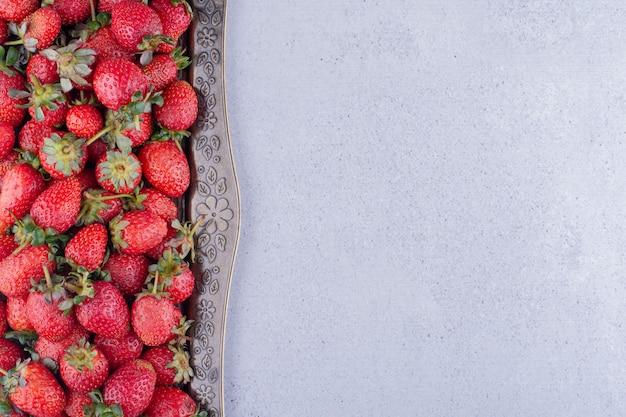 Erdbeeren serviert in einer reich verzierten Platte auf Marmorhintergrund. Foto in hoher Qualität