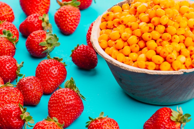 Erdbeeren und reife Sanddornbeeren auf Türkishintergrund