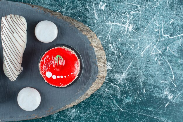 Erdbeerkuchen und verschiedene Süßigkeiten auf Holzstück.