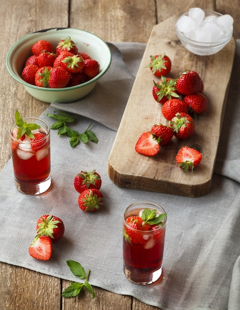 Erdbeertequilas nahe gehackten Erdbeeren auf einem Schneidebrett