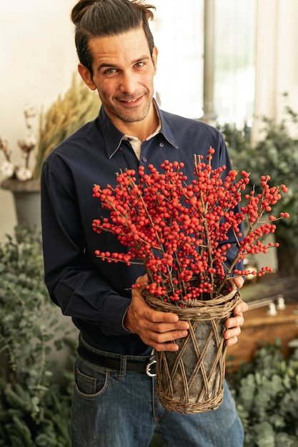 Kostenloses Foto erfahrener florist lächelt und hält rote pflanzen