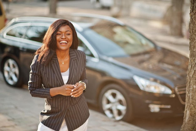 Erfolg stilvolle Afroamerikanerin in Jacke gegen schwarzes Auto