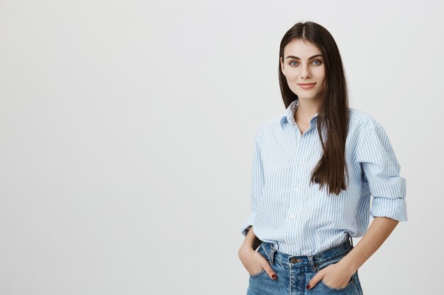 Erfolgreiche Frau in Hemd und Jeans mit Händen in den Taschen