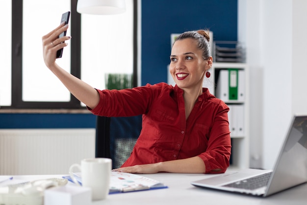 Erfolgreiche geschäftsfrau, die spaß an der arbeit hat und selfies macht