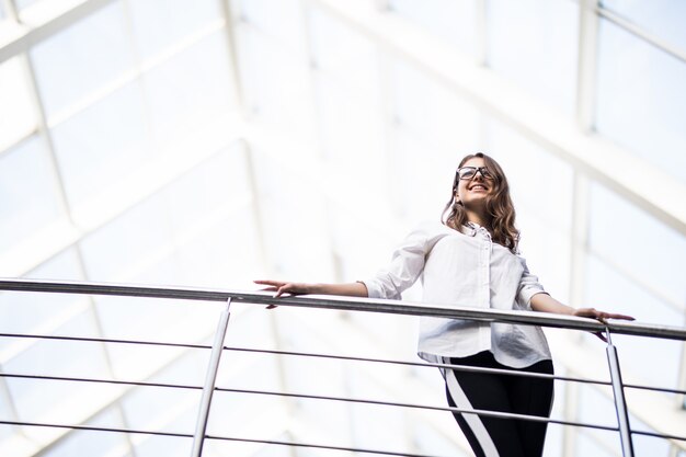 Erfolgreiche Geschäftsfrauen, die durch auf Balkon im modernen Bürozentrum schauen, gekleidet in weißem T-Shirt