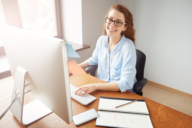 Erfolgreiche hübsche Geschäftsfrau, die am Computer im Büro arbeitet