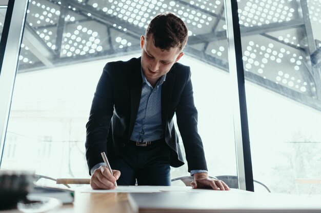 Erfolgreicher Geschäftsmann, der Dokumente in einem modernen Büro signiert