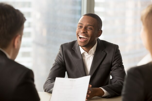 Erfolgreicher glücklicher schwarzer männlicher Kandidat, der eingestellt wurde, bekam einen Job