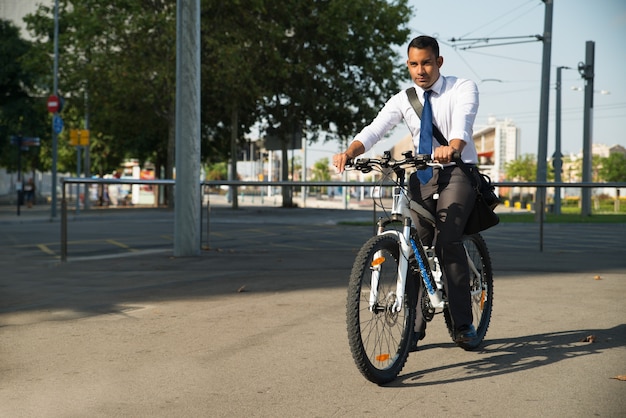 Erfolgreicher lateinischer Geschäftsmann, der Fahrrad zur Arbeit reitet
