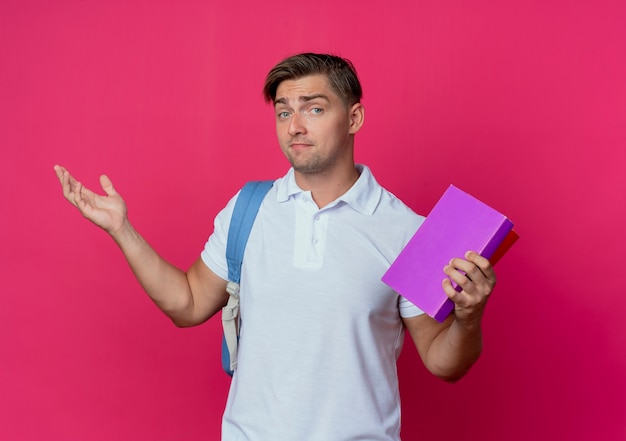 Erfreulicher junger hübscher männlicher Student, der Rückentasche hält Bücher hält