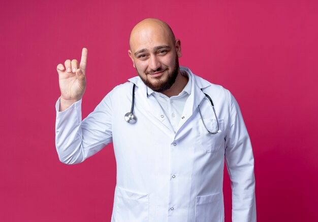Erfreulicher junger männlicher Arzt, der medizinische Robe und Stethoskop trägt