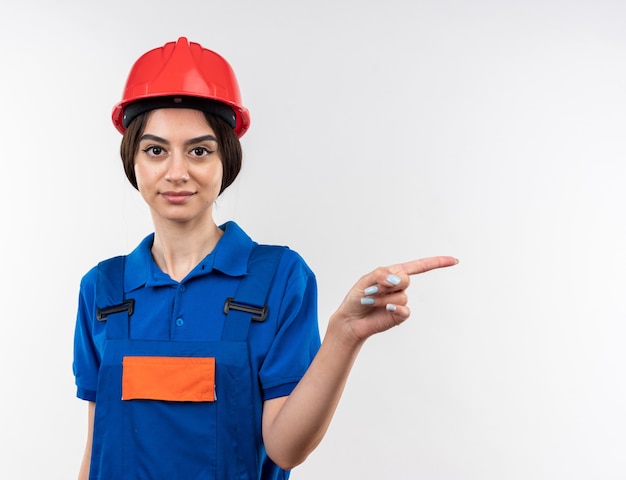 Erfreut Blick in die Kamera junge Baumeisterin in Uniform zeigt an der Seite