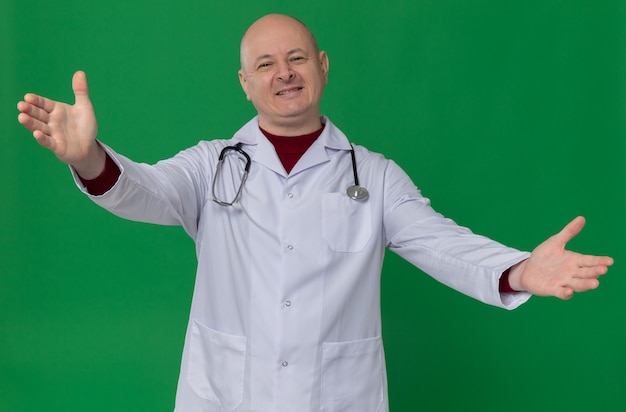 Erfreut erwachsener slawischer Mann in Arztuniform mit Stethoskop, das die Hände offen hält
