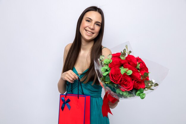 Erfreut kippendes schönes junges Mädchen mit Blumenstrauß mit Geschenktüte