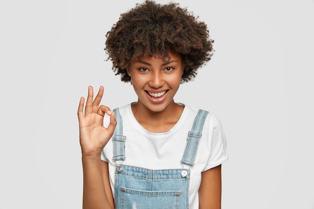 Erfreut zufriedener selbstbewusster afroamerikanischer teenager zeigt feines zeichen mit einer hand
