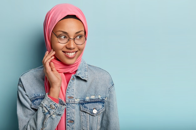 Erfreute dunkelhäutige Dame hat islamische Ansichten, trägt transparente Brille