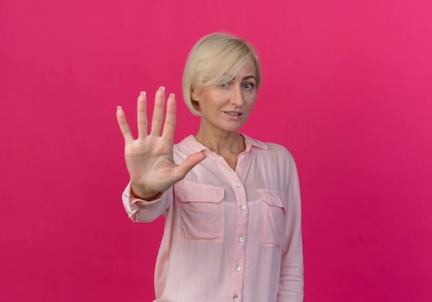 Erfreute junge blonde slawische Frau, die Kamera betrachtet und fünf mit Hand lokalisiert auf rosa Hintergrund mit Kopienraum zeigt