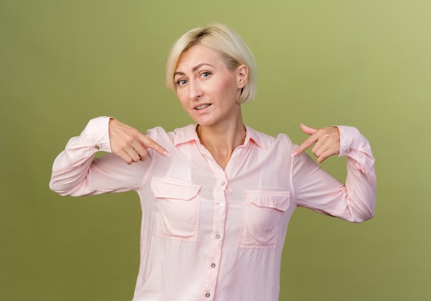 Erfreute junge blonde slawische Frau zeigt auf sich