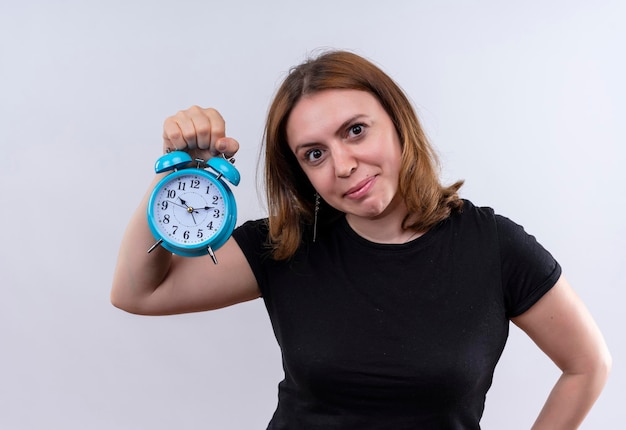 Kostenloses Foto erfreute junge lässige frau, die wecker auf isoliertem leerraum hält