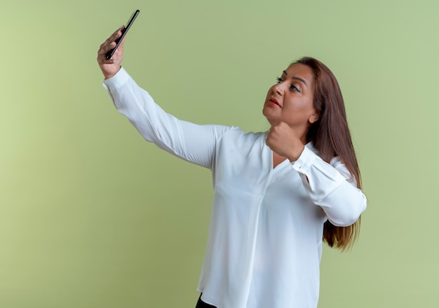 erfreute lässige kaukasische Frau mittleren Alters machen ein Selfie und halten die Faust