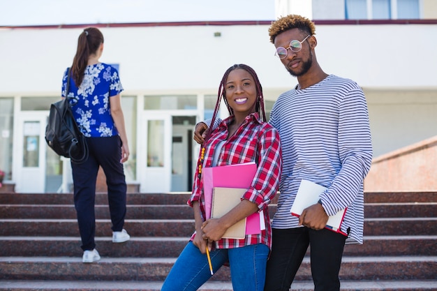 Erfreute schwarze Studenten posieren auf Treppen