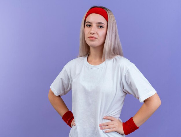 Erfreutes junges kaukasisches sportliches Mädchen mit Zahnspangen, die Stirnband tragen
