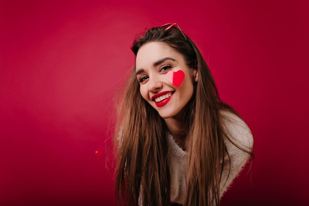 Erfreutes weißes Mädchen mit braunen Haaren, die zur Kamera lächeln