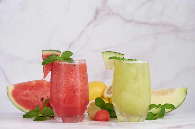 Erfrischender Sommerzitruscocktail mit Zitrone, Wassermelone und Melone mit Minze und Eiswürfeln im Glas