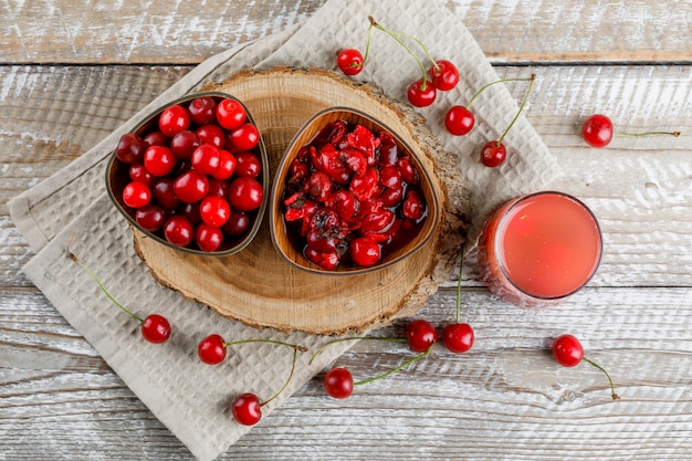 Erfrischungsgetränk mit Kirschen, Marmelade, Holzbrett in einem Krug auf Holz und Küchentuch.