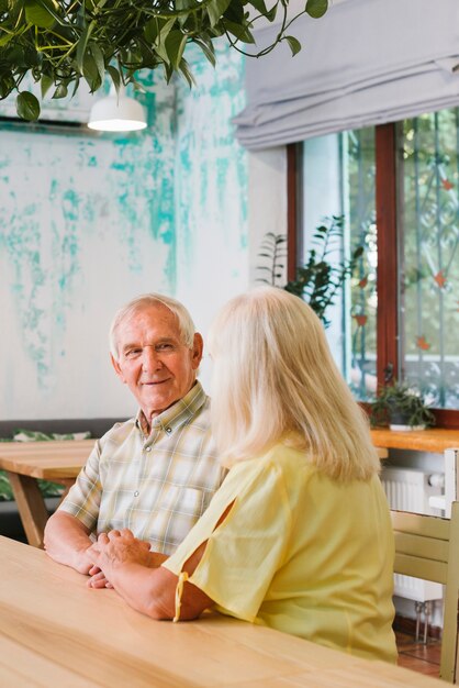 Erfüllte ältere Paare, die im Café und im Händchenhalten sitzen