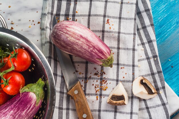 Erhöhte Ansicht der Aubergine; Pilz; Chili Flocke und Messer auf kariertem Mustertuch