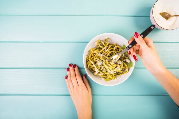 Erhöhte Ansicht der Hand einer Frau, die Spaghettis isst