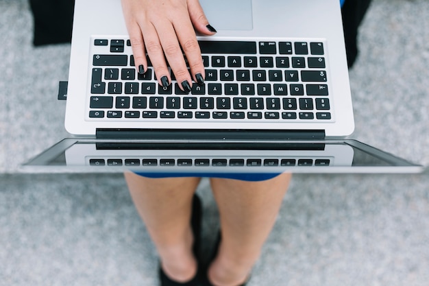 Erhöhte Ansicht der Hand einer Geschäftsfrau, die auf Laptoptastatur schreibt