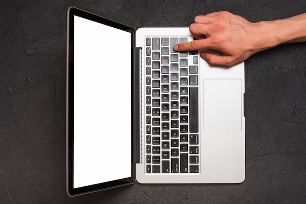 Erhöhte Ansicht der Hand einer Person unter Verwendung des Laptops auf schwarzem Hintergrund