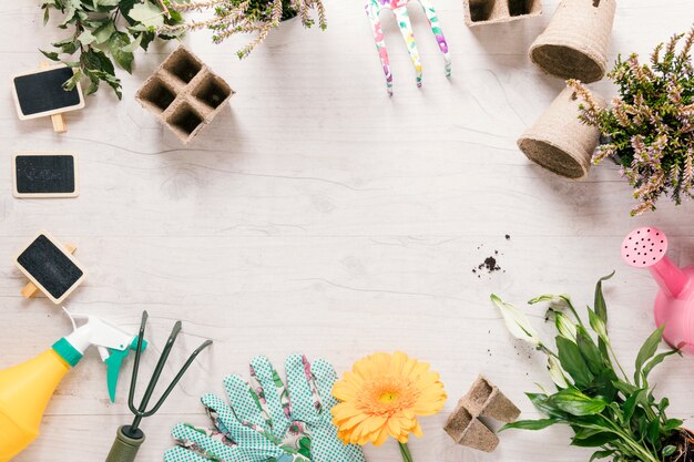 Erhöhte Ansicht der Pflanze; Gartenhandschuh; Blume; Rechen; Sprüher; Gießkanne; Torf Tablett und Stange auf Holz Schreibtisch